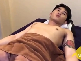 A young Asian man gives a sensual massage with his hands to another young Asian man.